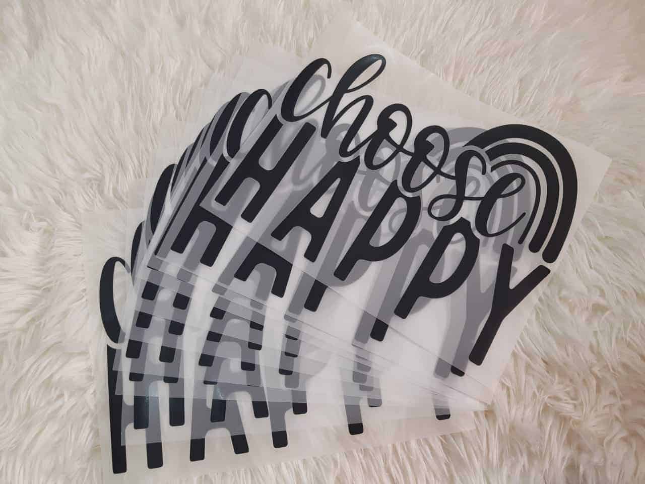 transparent heat transfer direct to film plastic films for a text printing on clothing says "CHOOSE" in stylish font on top and flat text "HAPPY" in blank ink