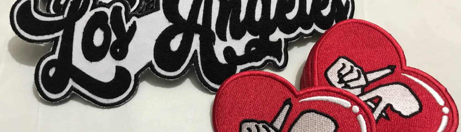 los angles patches in big black yarn thread on white for front of clothing and small red fill stitch hands gesture LA in center