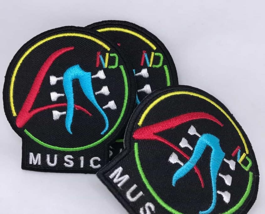 black twill fabric embroidered patch show dancing legs in cyan white, red, green and yellow thread for white embroidered MUSIC in bottom