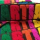 Bulk chenille felt patches in multi color spread that says ‘MARTIAN’ in caps lock capital English alphabet. M in blue yarn, A in green, R in red, T in orange, I in pink, A in yellow and N in fluffy purple on the black scrim felt and twill. The script letters show cut off scars passing through entire wording.