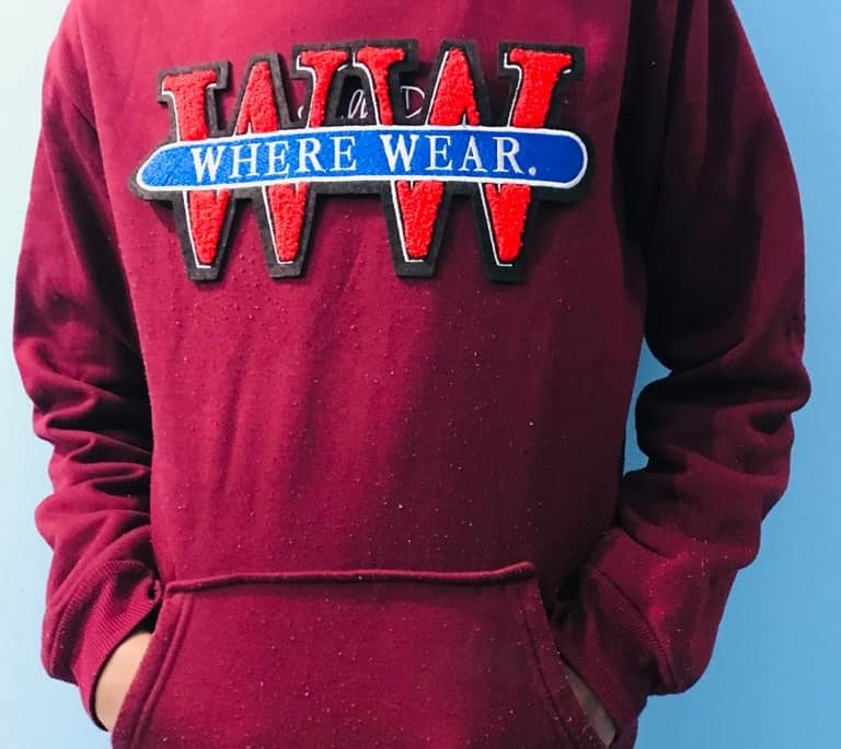 boy wears maroon hoodie with a brand name chenille patch WHERE WEAR yarn mixed satin embroider front patch in front of sky blue wall