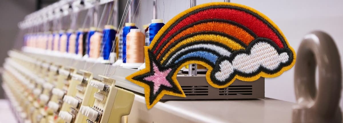 a machine for custom embroidery in background shows colorful rainbow logo embroidered in multi color viscose thread 