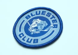 light blue background BLUESTER CLUB with pet in centre circle woven label for custom use have royal blue merrowed border